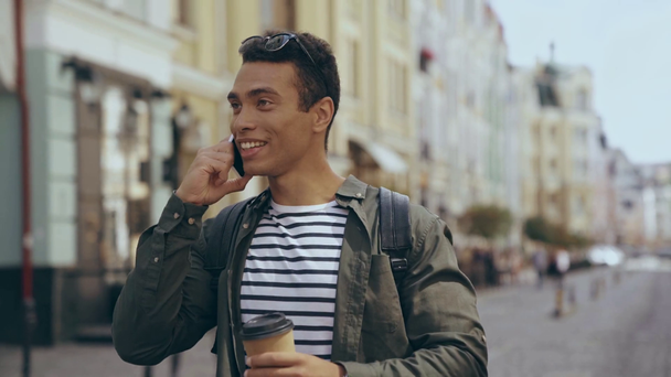 διαφυλετικός άνθρωπος πίνοντας καφέ και μιλώντας στο smartphone στο δρόμο - Πλάνα, βίντεο