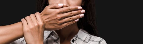 panoramic shot of scared young woman covering mouth isolated on black  - Foto, imagen