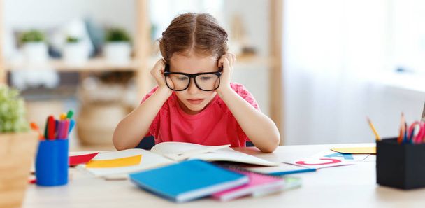 втомлена дівчинка робить домашнє завдання вдома
 - Фото, зображення