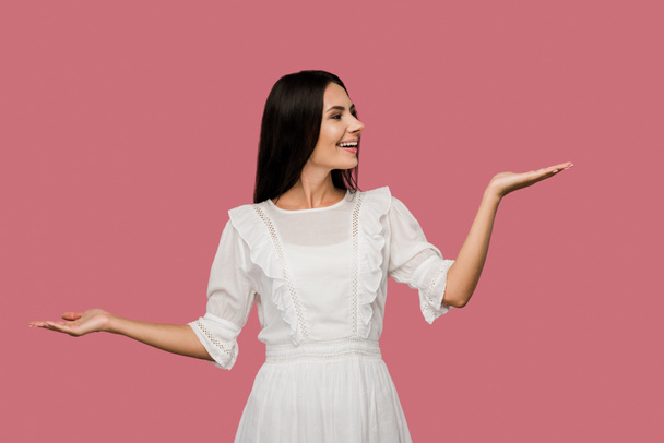 cheerful woman in white dress gesturing isolated on pink  - Foto, immagini