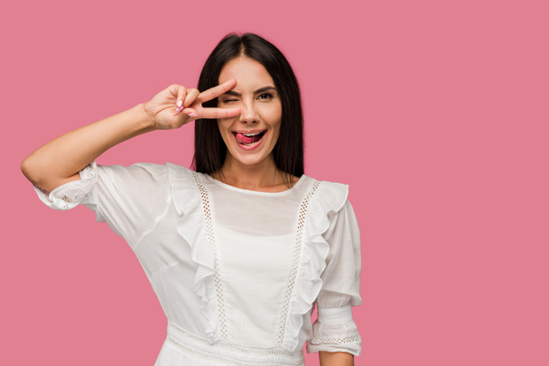 happy woman in dress showing tongue and peace sign isolated on pink  - Photo, Image