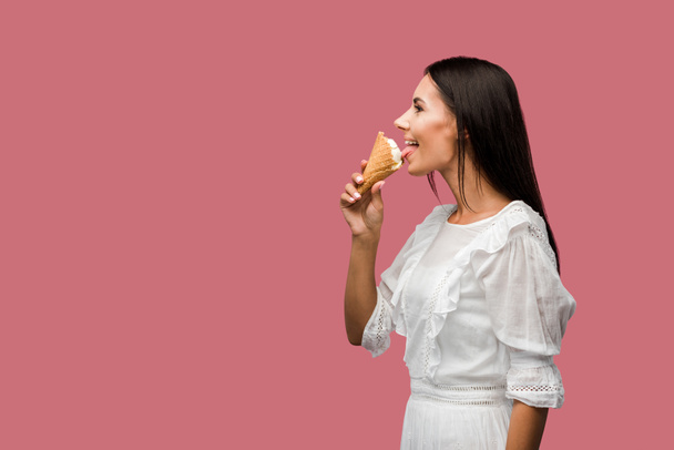 side view of happy woman eating tasty ice cream isolated on pink  - Foto, Imagem