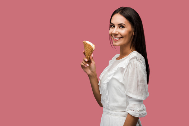 cheerful girl in dress holding ice cream cone isolated on pink  - Фото, изображение
