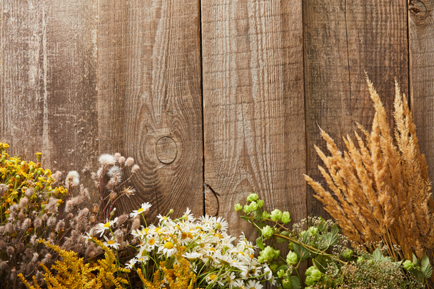 Top uitzicht van wilde bloemen en kruiden op houten oppervlak met Kopieer ruimte - Foto, afbeelding