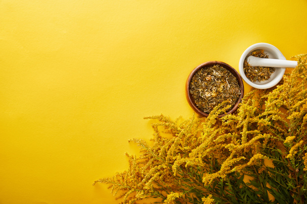 top view of mortars with herbal blend near goldenrod bunches on yellow background - Photo, Image
