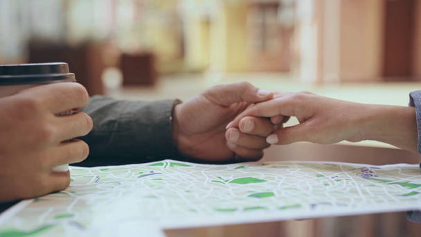 περικομμένη όψη του ζευγαριού κρατώντας τα χέρια κοντά στο χάρτη - Πλάνα, βίντεο
