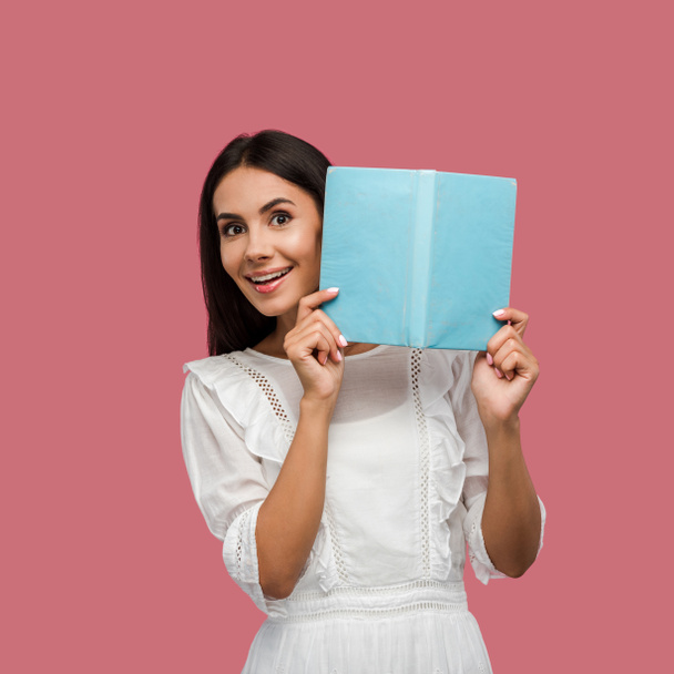 happy woman in white dress holding blue book isolated on pink  - Photo, Image