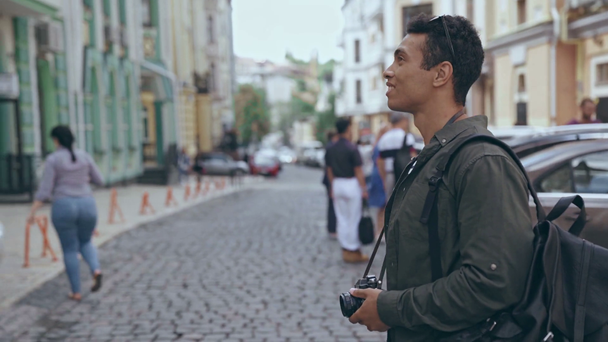 KYIV, UKRAINE - JULY 9, 2019: bi-racial man with camera crossing street - Materiał filmowy, wideo