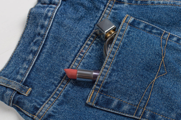 Perfume and lipstick in a pocket of blue jeans. - 写真・画像