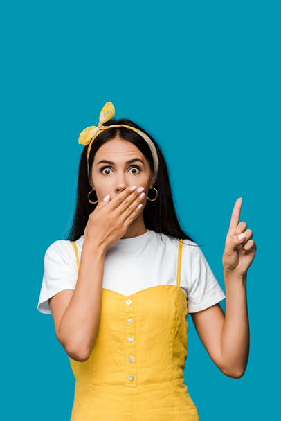 потрясенная девушка, прикрывающая рот, указывая пальцем, изолированным на синий
  - Фото, изображение