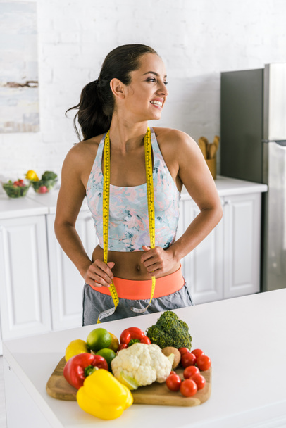 cheerful woman holding measuring tape near fruits  - Foto, imagen