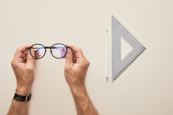 abgeschnittene Ansicht eines Mannes mit Brille isoliert auf beige  - Foto, Bild