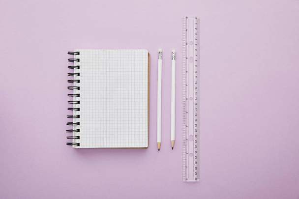 top view of notebook near pencils and ruler isolated on purple  - Foto, afbeelding