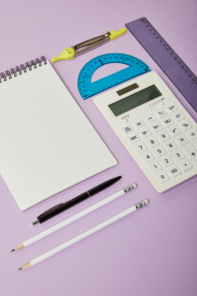 linijki i kalkulator w pobliżu notebooka i papeterii izolowane na fioletowym  - Zdjęcie, obraz