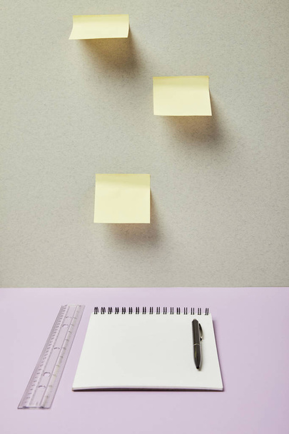 blank notebook near pen, ruler and sticky notes on grey and purple  - Photo, Image