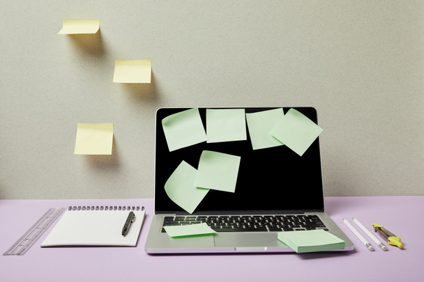 green sticky notes on laptop near stationery on grey and purple  - 写真・画像