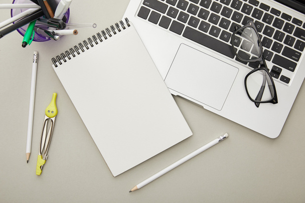 top view of notebook near stationery and laptop isolated on grey  - Photo, Image