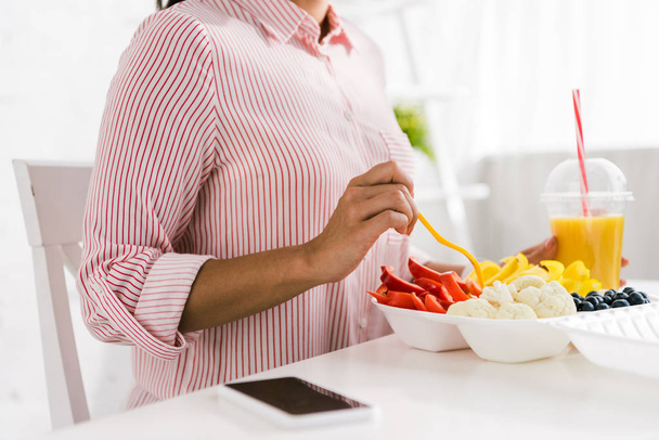 rajattu näkymä nainen tilalla haarukka lähellä ruoka kontti vihanneksia
  - Valokuva, kuva
