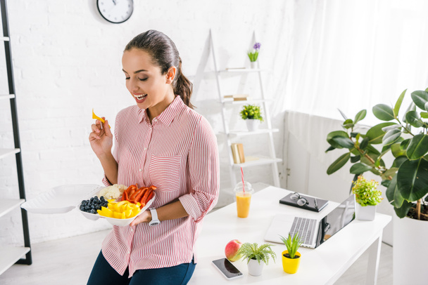 szczęśliwy dziewczyna trzyma plastikowy widelec w pobliżu warzyw w pojemniku żywności  - Zdjęcie, obraz