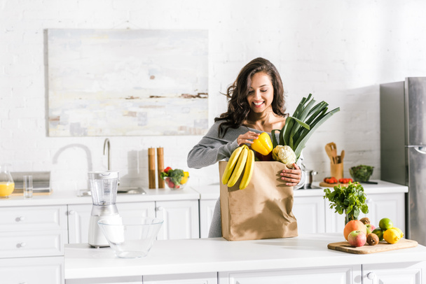 lezzetli gıda ile kağıt torba yakınında duran mutlu kadın  - Fotoğraf, Görsel