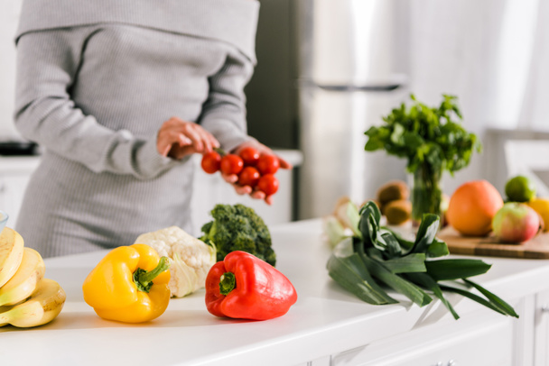 selective focus of fresh vegetables near woman in kitchen  - Foto, afbeelding