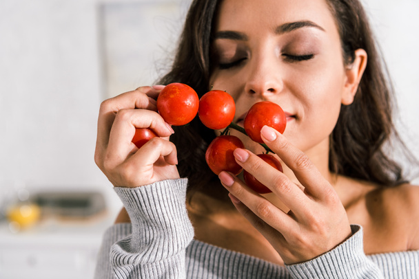 aantrekkelijke vrouw ruikende rijpe cherry tomaten  - Foto, afbeelding