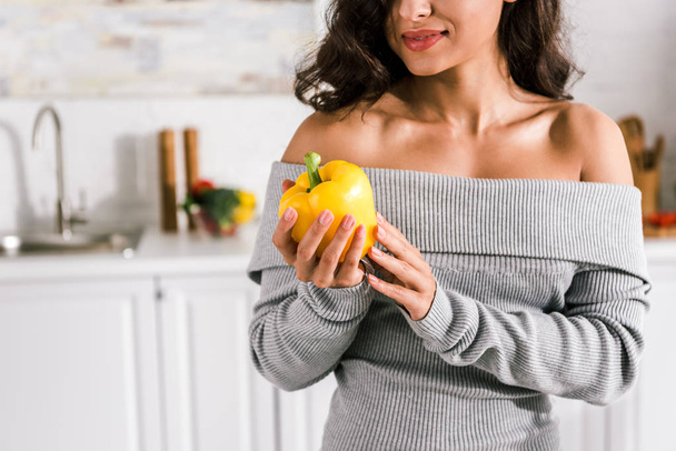 cropped view of happy woman holding yellow tasty paprika in hands  - Foto, imagen