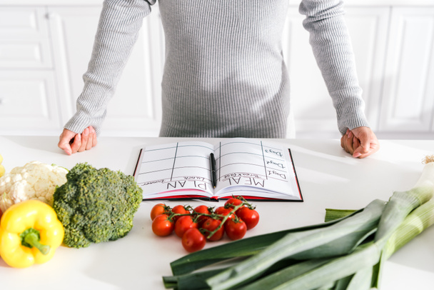обрізаний вид жінки, що стоїть з прикутими кулаками біля овочів
  - Фото, зображення
