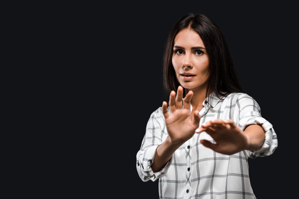 stressed woman gesturing while looking at camera isolated on black  - Foto, Bild