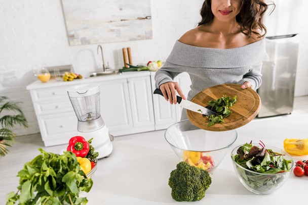 cropped view of girl holding cutting board near bowl with vegetables   - Photo, Image