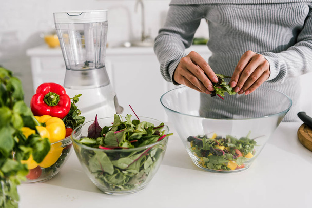 cropped view of woman preparing salad in kitchen  - Foto, Bild