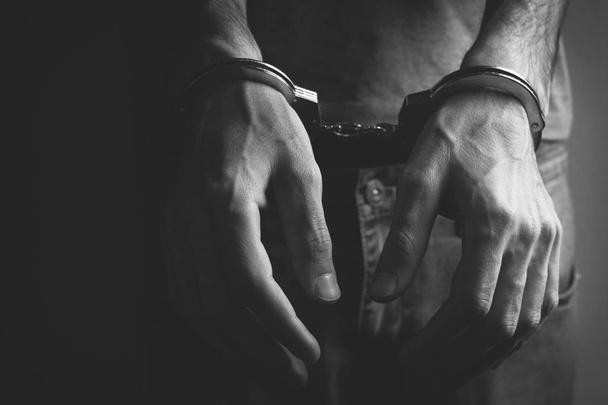 young man hand handcuffs on dark background - Foto, Imagem
