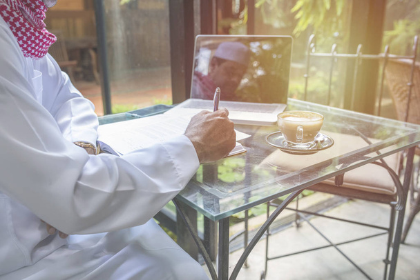 arabischer muslimischer Geschäftsmann arbeitet und schreibt mit Notizbuch auf dem Tisch im Café, freiberufliches Geschäftskonzept. - Foto, Bild