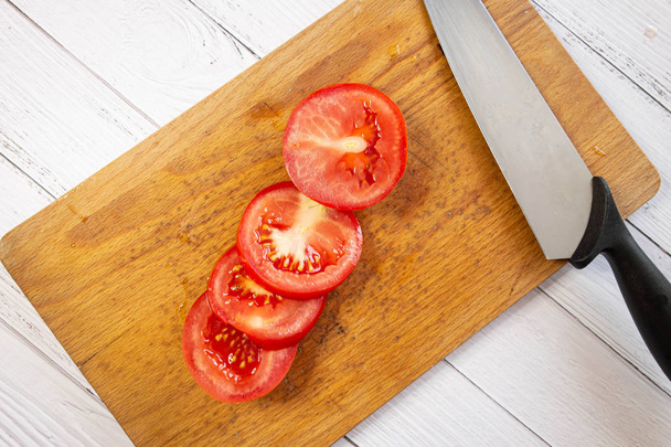 Świeże, soczyste, czerwone i smaczne pomidory w plasterków. Lekkie tło i ładne światło. Żywność ekologiczna i naturalna dla wegetarian i osób na diecie. Ilustracja żywności warzywnej - Zdjęcie, obraz