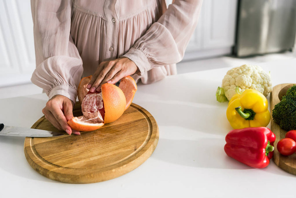 rajattu näkymä raskaana oleva nainen kuorinta greippi lähellä vihanneksia
  - Valokuva, kuva