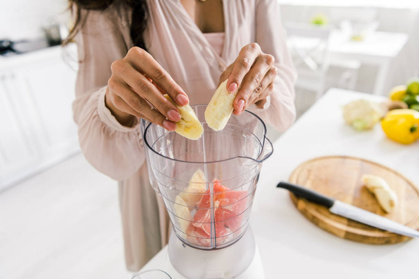 cropped view of pregnant woman putting banana in blender with grapefruit  - Foto, Imagem