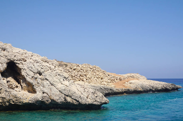 Blick auf einen kleinen Felsen, der an einem sonnigen Tag ins Meer ragt. Erholung auf See, Tourismus, Urlaub. schöner Blick auf die Küste - Foto, Bild