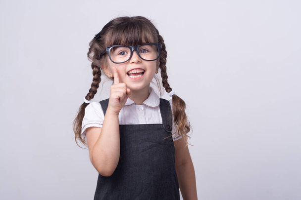 Cleveres Kind in Brille und Schuluniform. Geniales Kind. Kinder und tolle Idee. Saubere Frisur. kleines Mädchen mit niedlichen Zöpfen.  - Foto, Bild