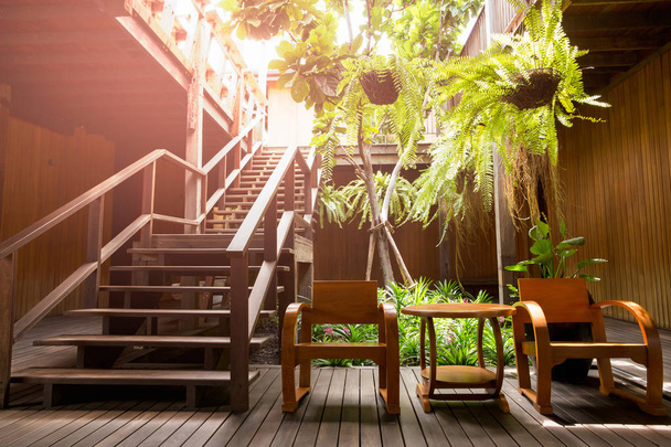 Escalera de madera con sillón y planta en terraza
. - Foto, Imagen