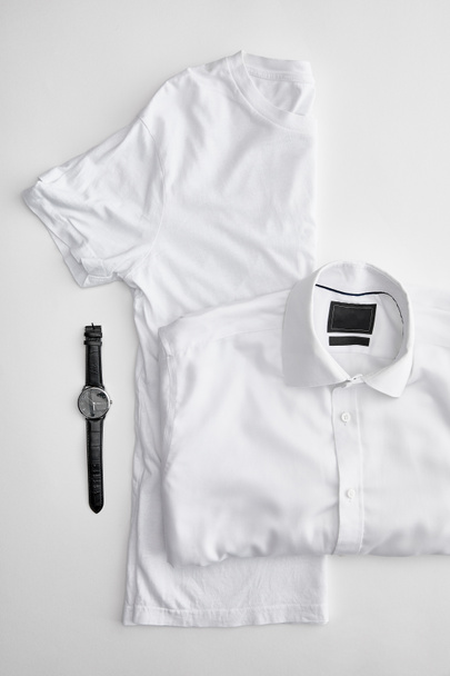vue du dessus de plié en demi-t-shirt près de chemise à carreaux et montres sur fond blanc
 - Photo, image