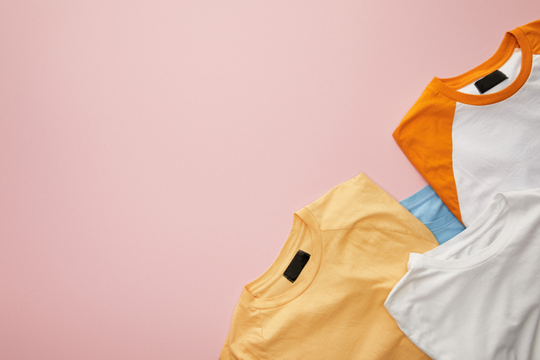 top view of color folded t-shirts on pink background - Fotó, kép