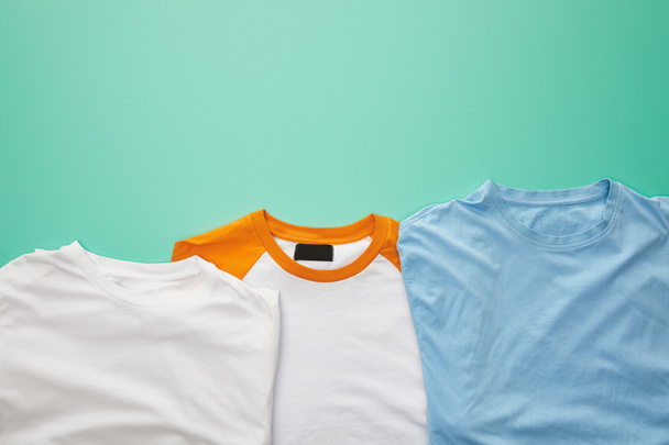 top view of folded plaid color t-shirts on turquoise background - Fotó, kép