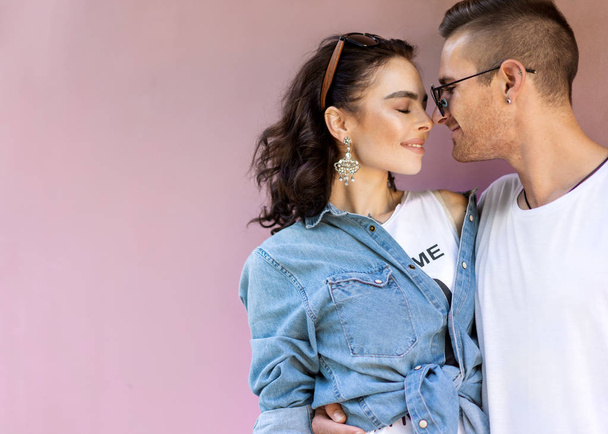 fashion couple in sunglasses posing on pink wall - Foto, Imagen