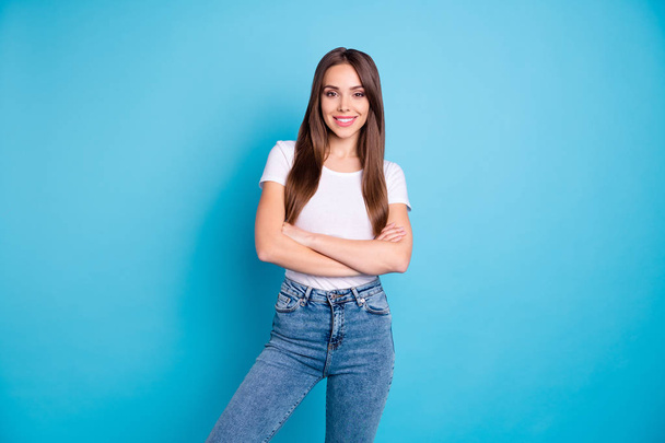 Portrait of gorgeous lady with her arms crossed looking at camera smiling wearing white t-shirt jeans denim isolated over blue background - Photo, Image