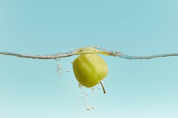 ripe green apple in water with bubbles on blue background - Photo, Image