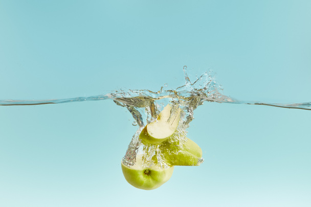 cut green apple in water with bubbles on blue background - Photo, Image