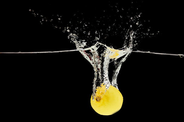 Свежий лимон падает глубоко в воду с брызги изолированы на черный
 - Фото, изображение
