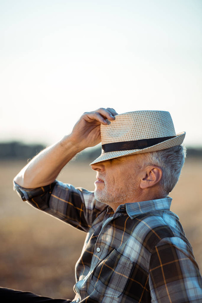 granjero autónomo con ojos cerrados tocando sombrero de paja
   - Foto, Imagen