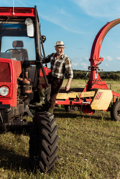 granjero senior autónomo cerca de tractor moderno
  - Foto, Imagen