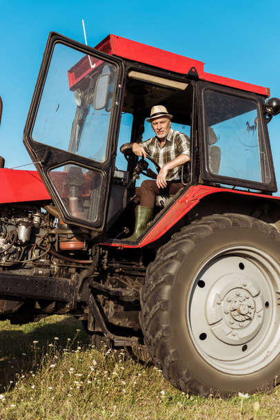 agricoltore autonomo senior in cappello di paglia trattore guida
  - Foto, immagini